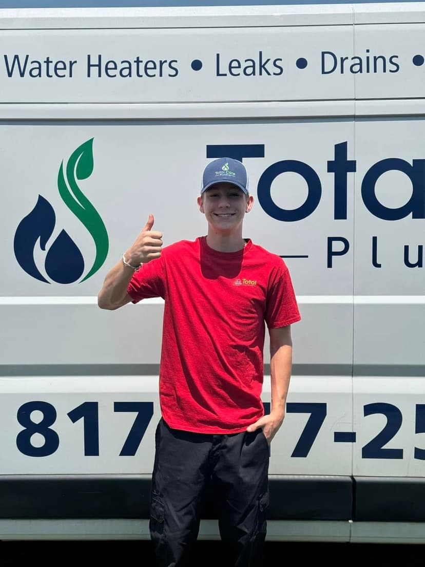 Young technician giving a thumbs up in front of a service van for plumbing and water heater solutions.